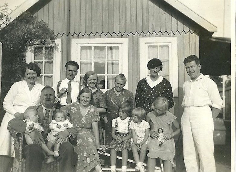 I et sommerhus. Det er sandsynligvis Jørgen og Mogens der sidder på skødet hos farfar. De tre små piger forrest er nok Åse, Inge og Bendte.
